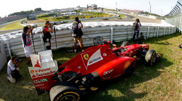 Fotógrafos trabajan junto al Ferrari de Fernando Alonso, retirado tras sufrir un accidente en el circuito de Suzuka (2012). Foto: EFE